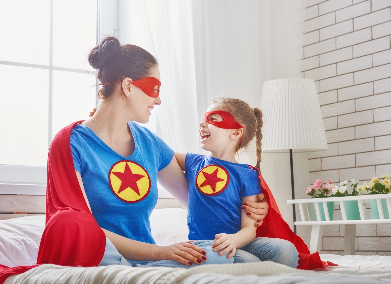 Mother and her child playing together. Girl and mom in Superhero