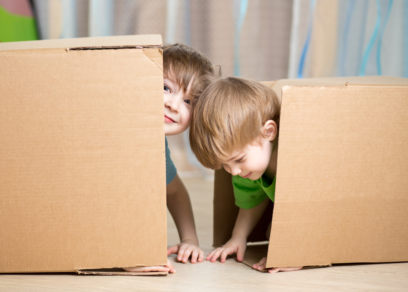 Child and toddler brothers playing in cardboard boxes